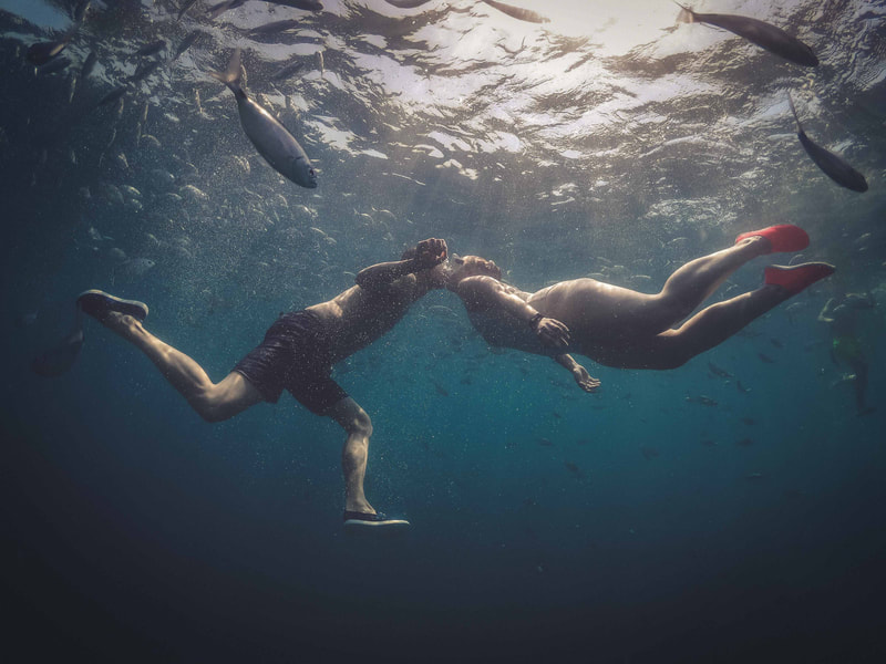 Underwater romance: A couple snorkeling and sharing a kiss amidst vibrant marine life and clear blue waters.