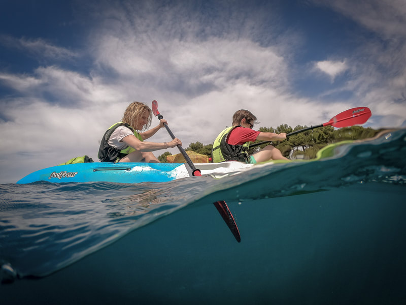 A mother and son enjoying a kayaking adventure together, paddling along the beautiful coast of Pula
