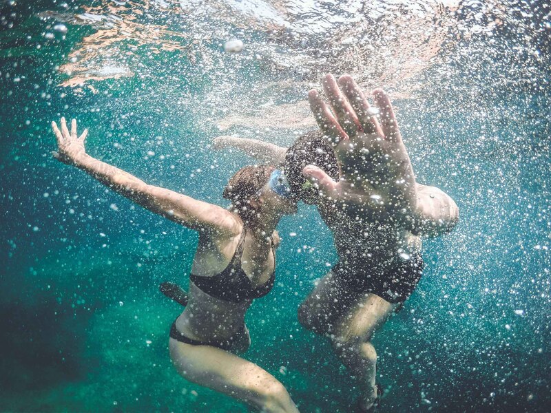 Snorkeling couple sharing a tender kiss underwater, surrounded by the beauty of the aquatic world.